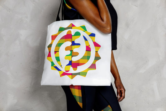 Person holding a colorful tote bag with a geometric design against a neutral background