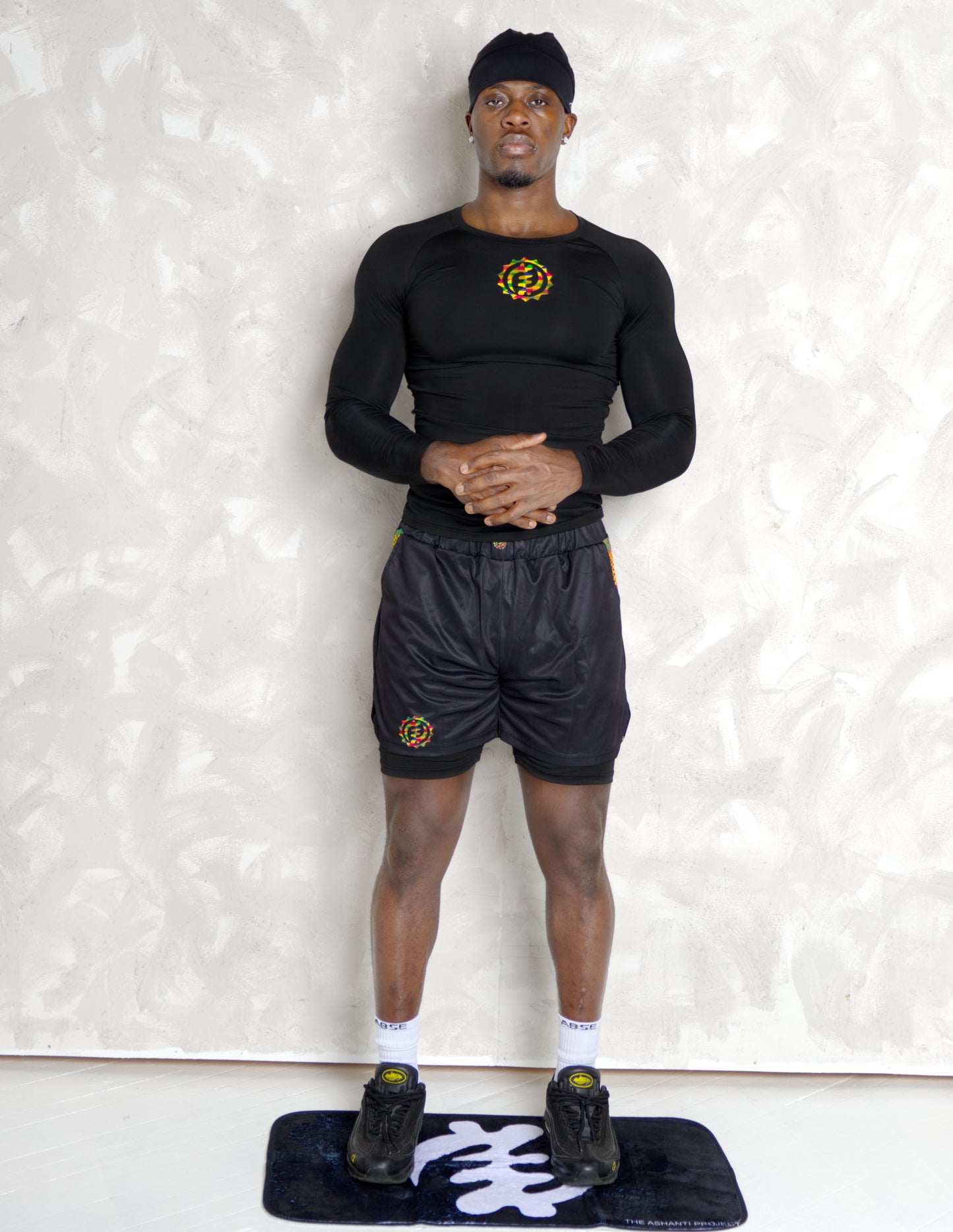 Person wearing a black athletic outfit with kente logos on a white background. comes with a compression shorts