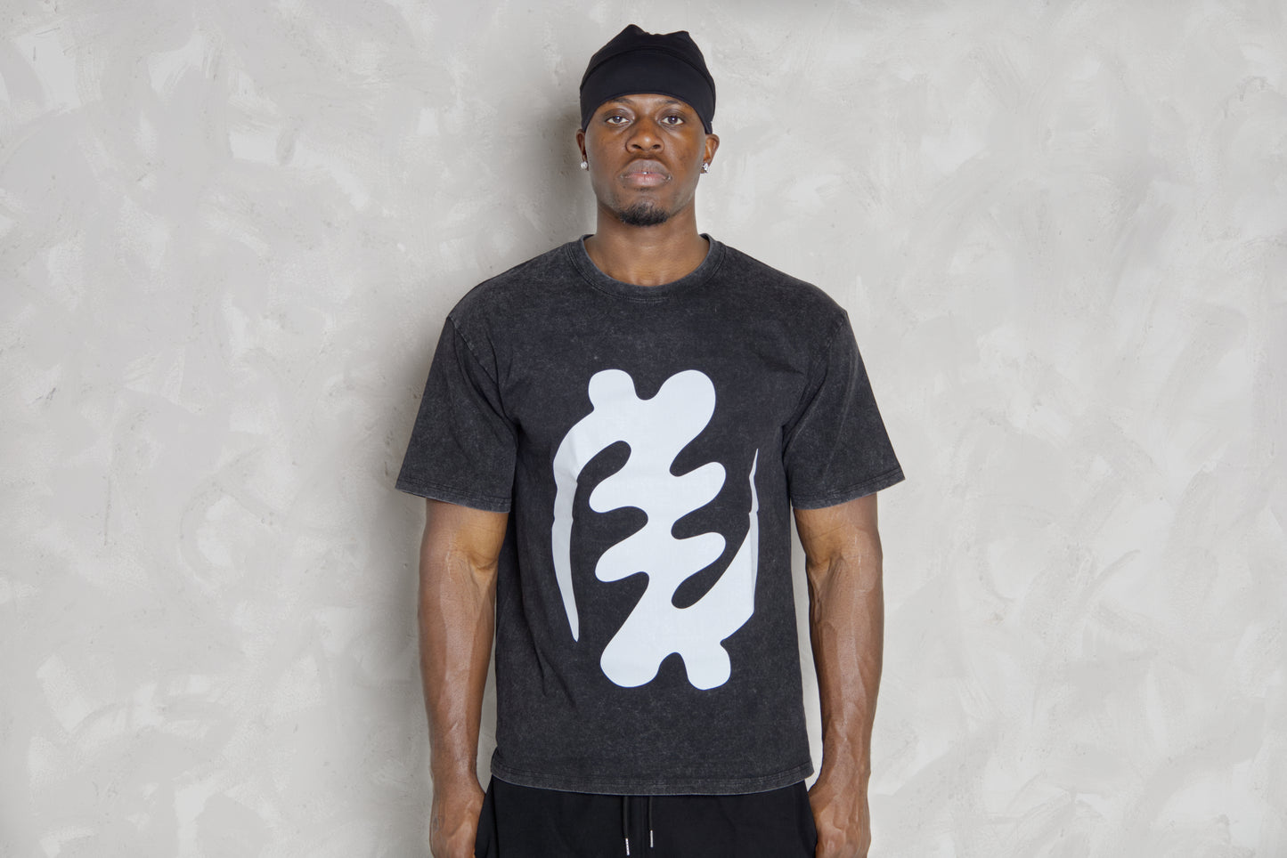 Person wearing a black t-shirt with a white logo against a light gray background