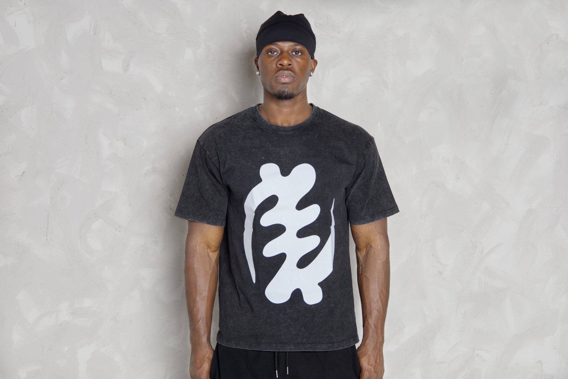 Person wearing a black t-shirt with a white logo against a light gray background
