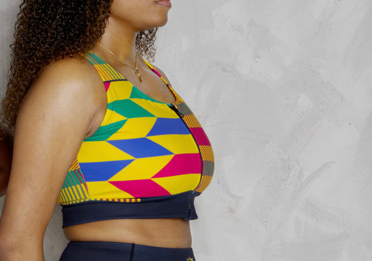 Woman wearing a colorful geometric-patterned sports bra and shorts on a plain background