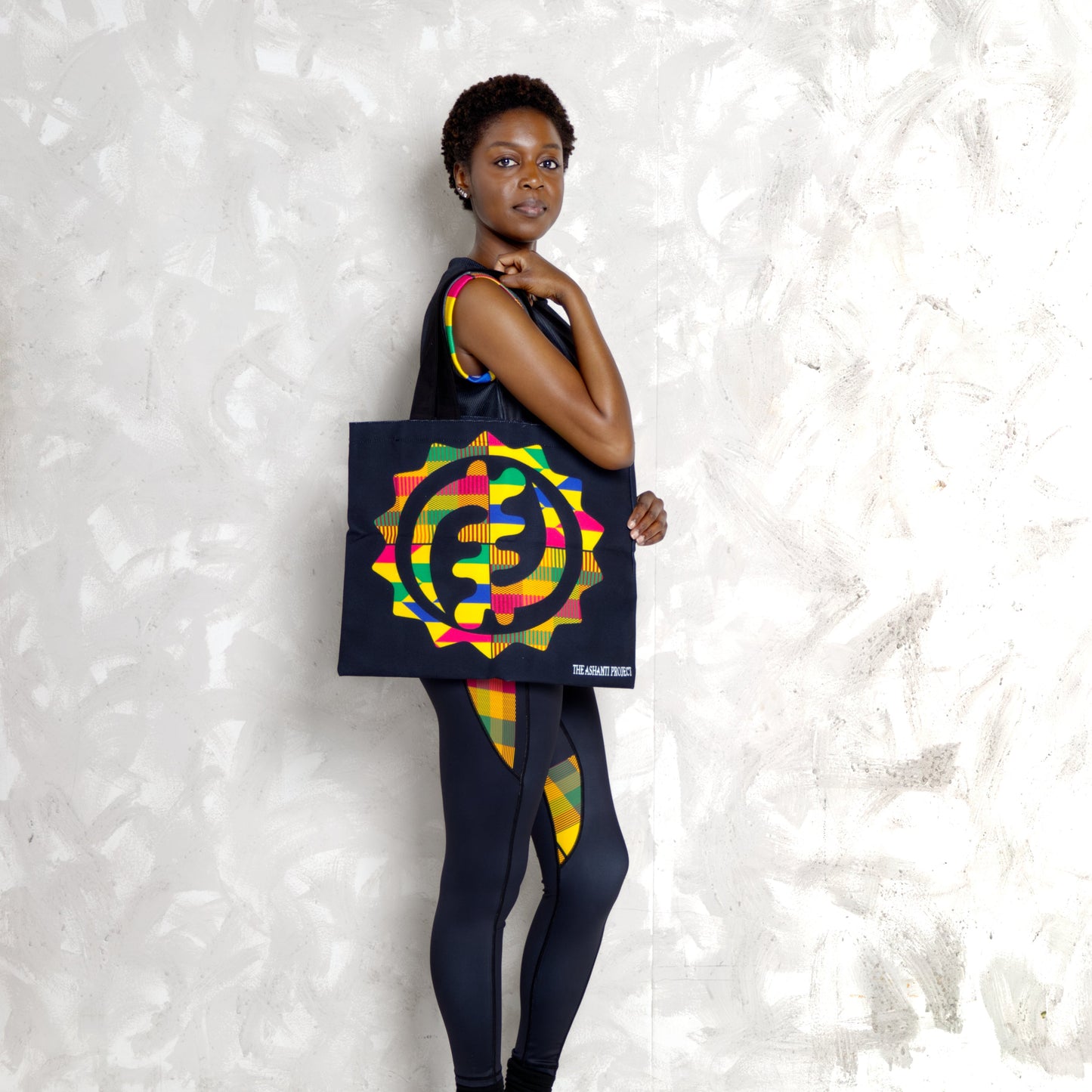 Person wearing a colorful outfit with a tote bag featuring a geometric design.