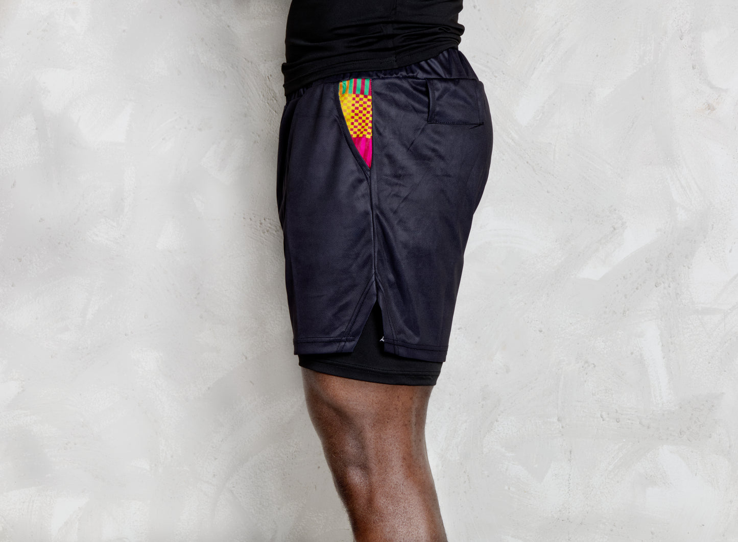 Person wearing a black athletic outfit with kente  logos on a white background. comes with a compression shorts 