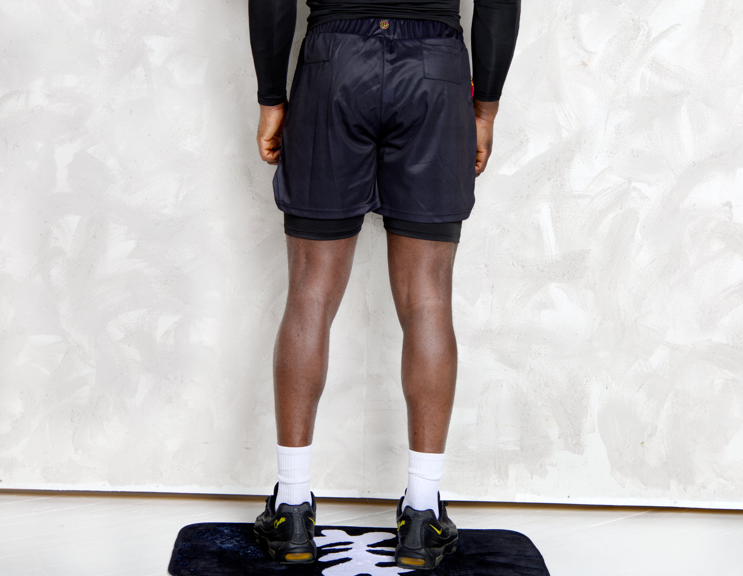 Person wearing a black athletic outfit with kente  logos on a white background. comes with a compression shorts 