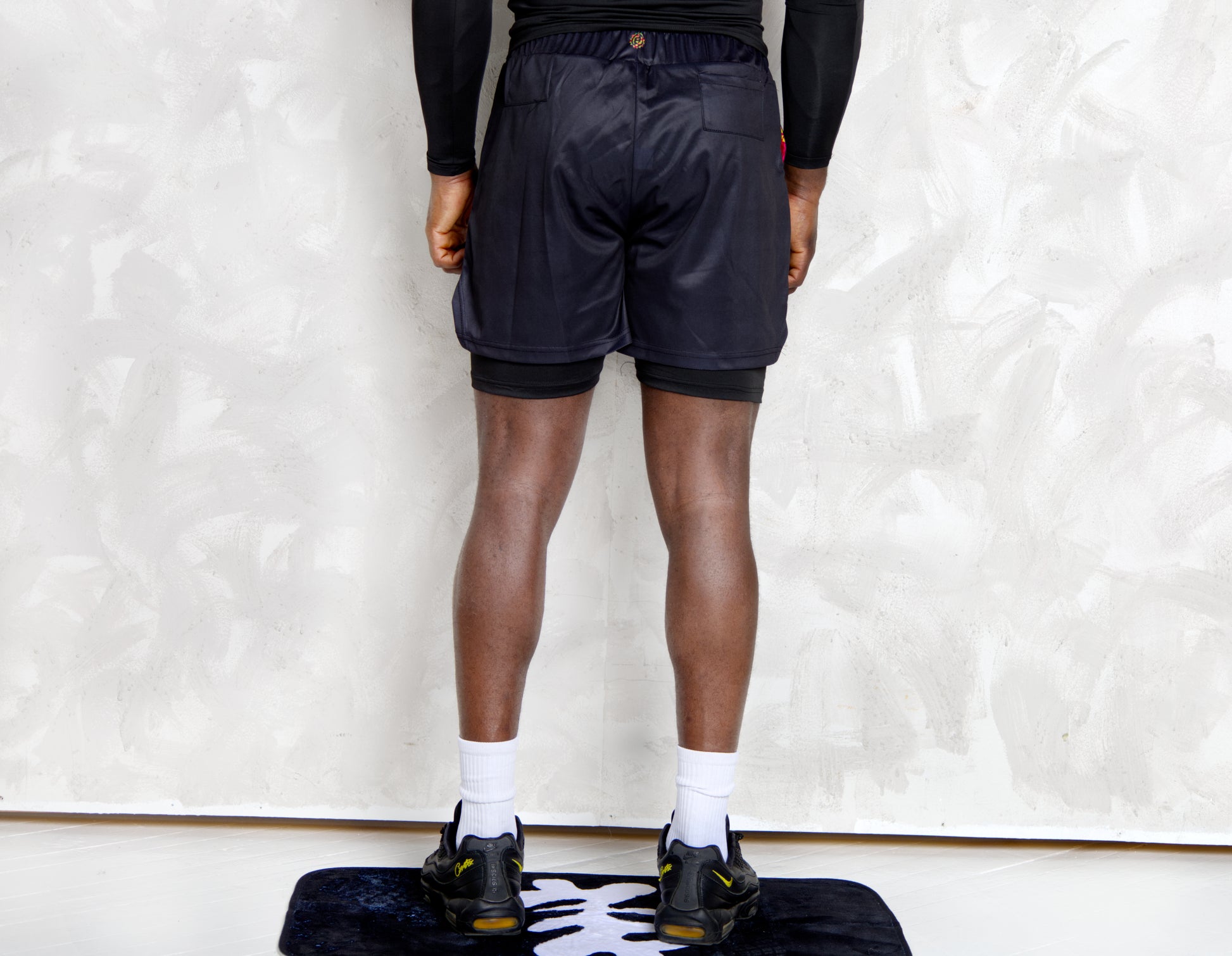 Person wearing a black athletic outfit with kente  logos on a white background. comes with a compression shorts 