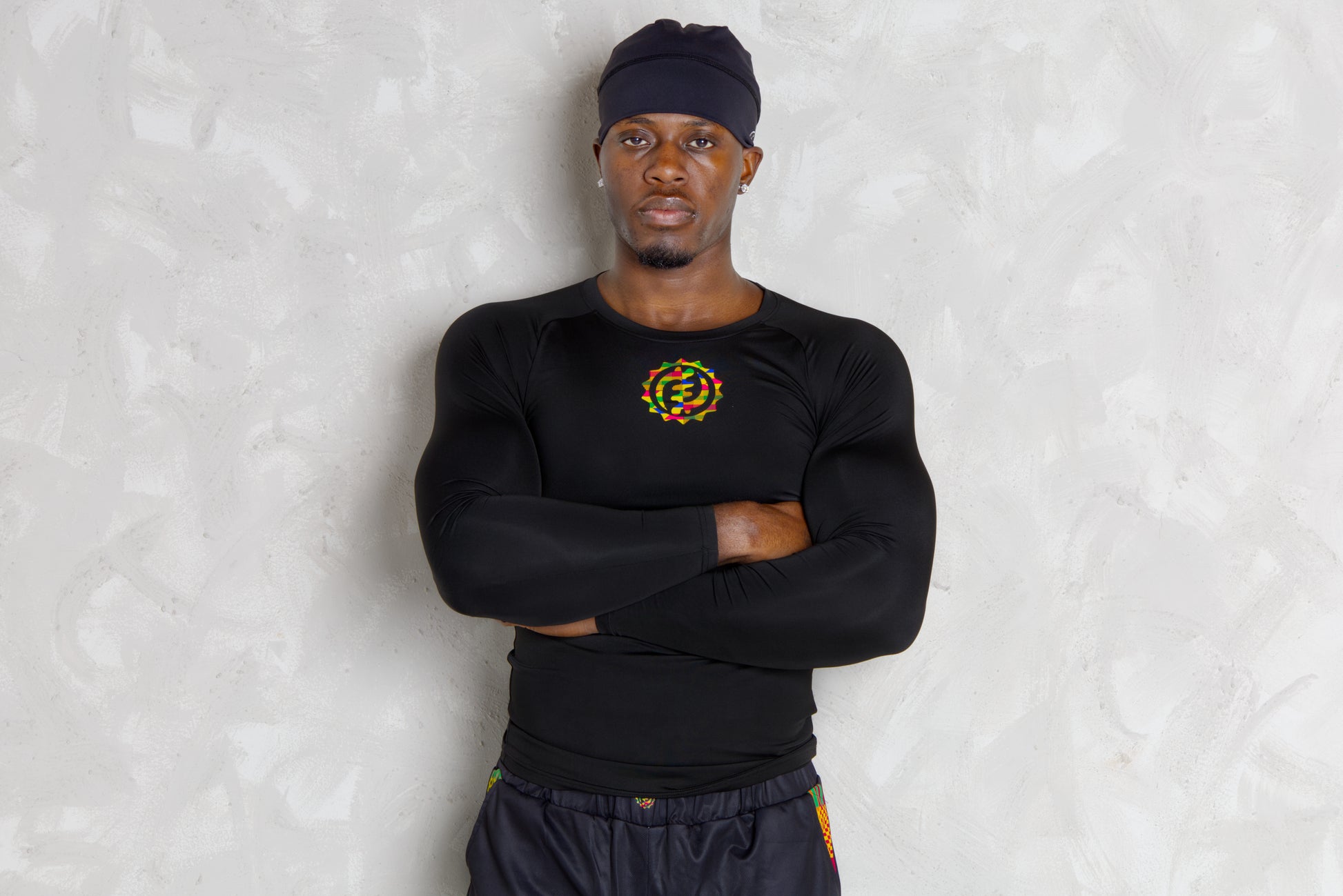 Person wearing a black athletic outfit with kente  logos on a white background. comes with a compression shorts 