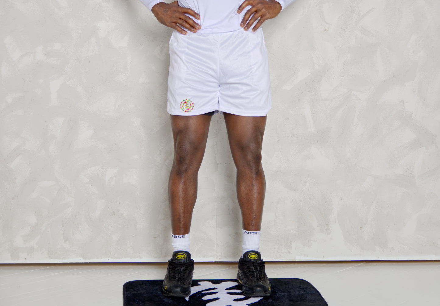 Person wearing white shorts and black shoes on a white background
Black Man wearing active long sleeve kente shirt and white shorts with compression 