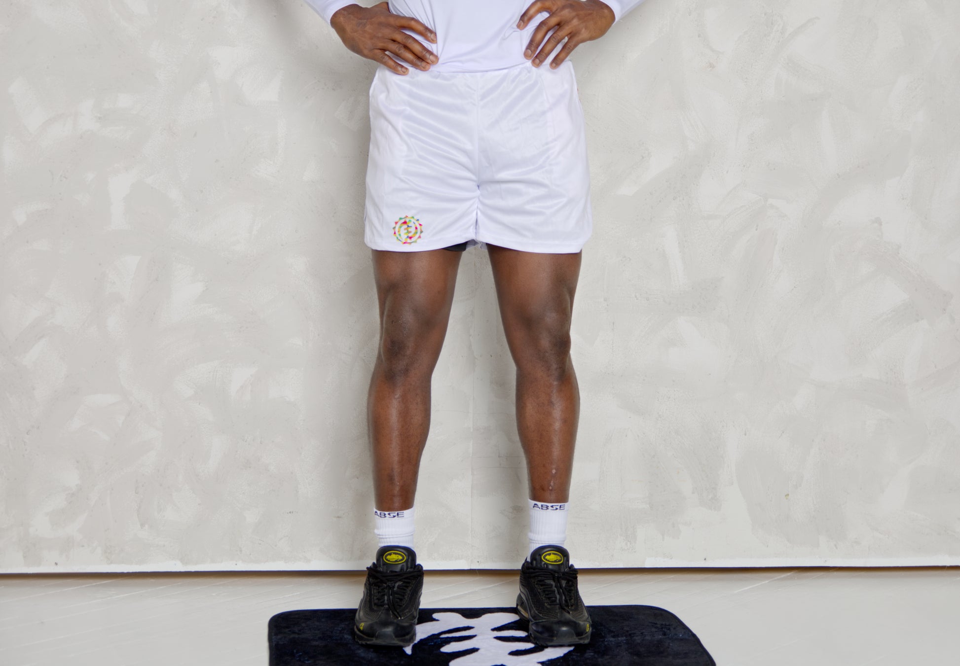 Person wearing white shorts and black shoes on a white background
Black Man wearing active long sleeve kente shirt and white shorts with compression 