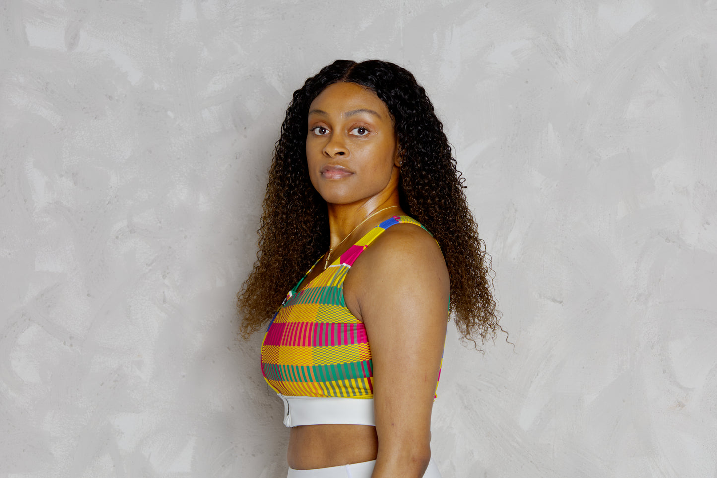 Woman wearing a colorful striped top against a plain background
Black woman wearing white leggings with colorful kente designs on a plain background. Athletic wear. Gym outfit, 