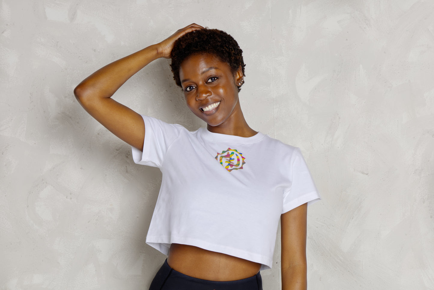 Woman wearing a white t-shirt with a colorful logo against a plain background