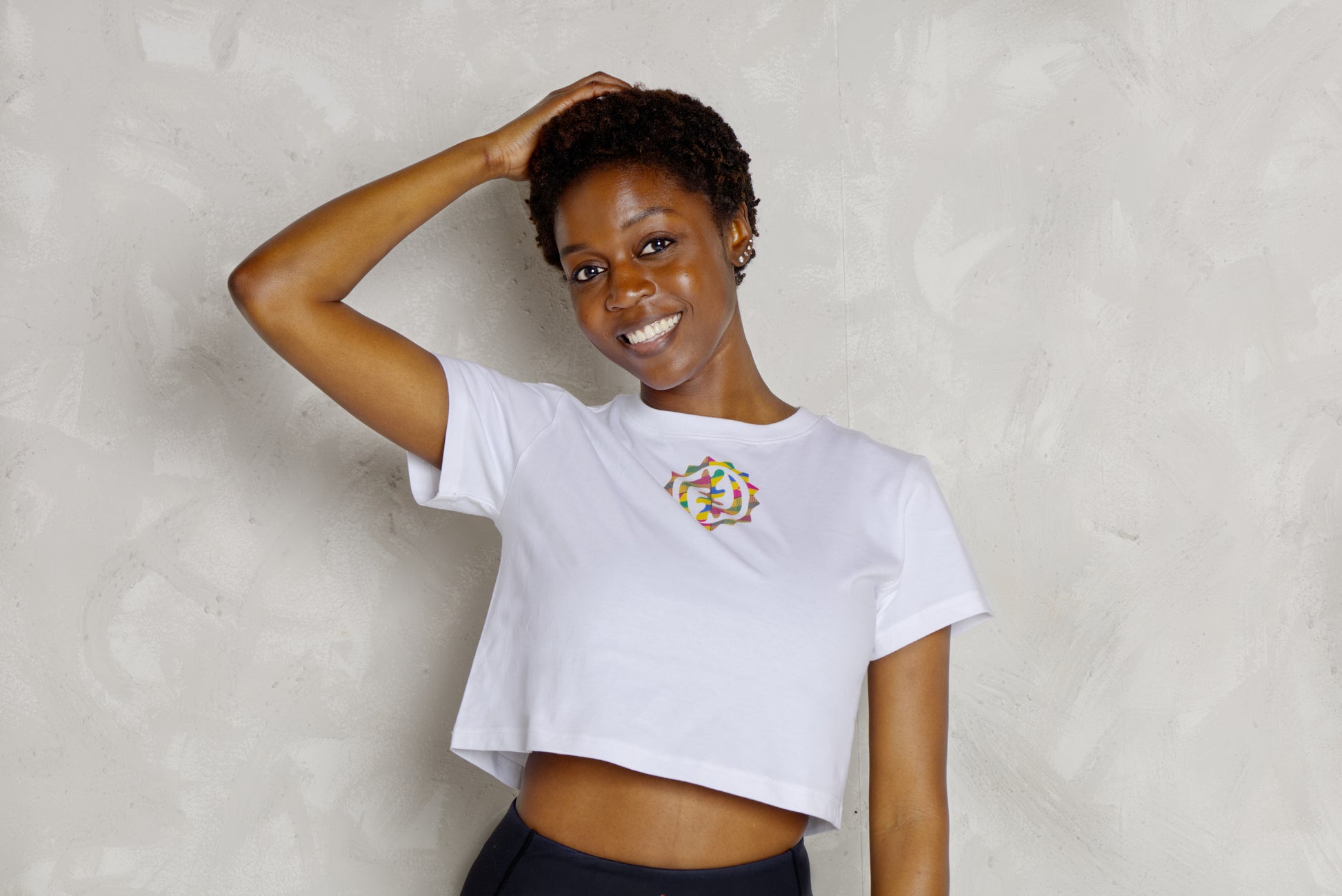 Woman wearing a white t-shirt with a colorful logo against a plain background