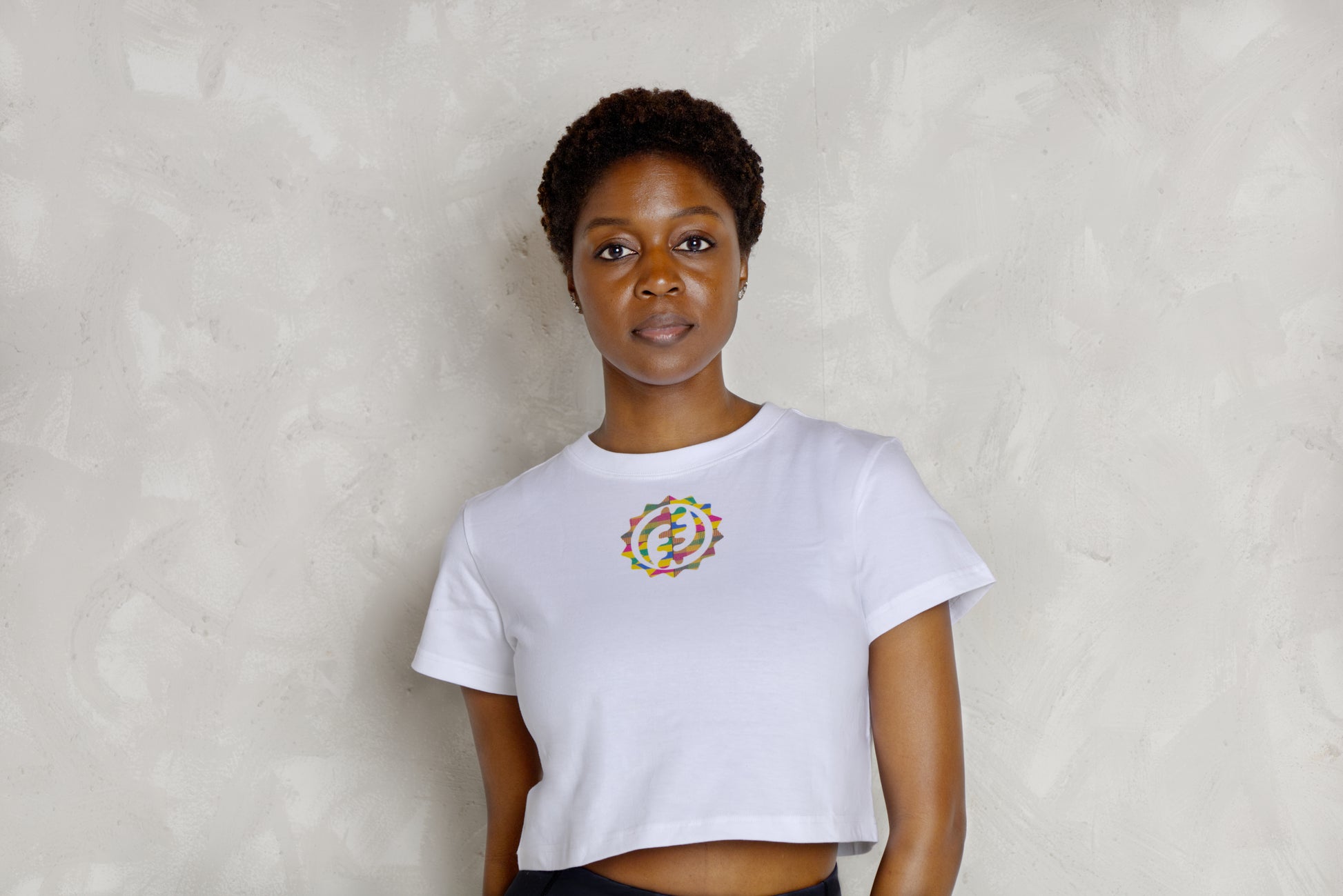 Person wearing a white t-shirt with a colorful circular design against a plain background
Black woman wearing white leggings with colorful kente designs on a plain background. Athletic wear. Gym outfit, 