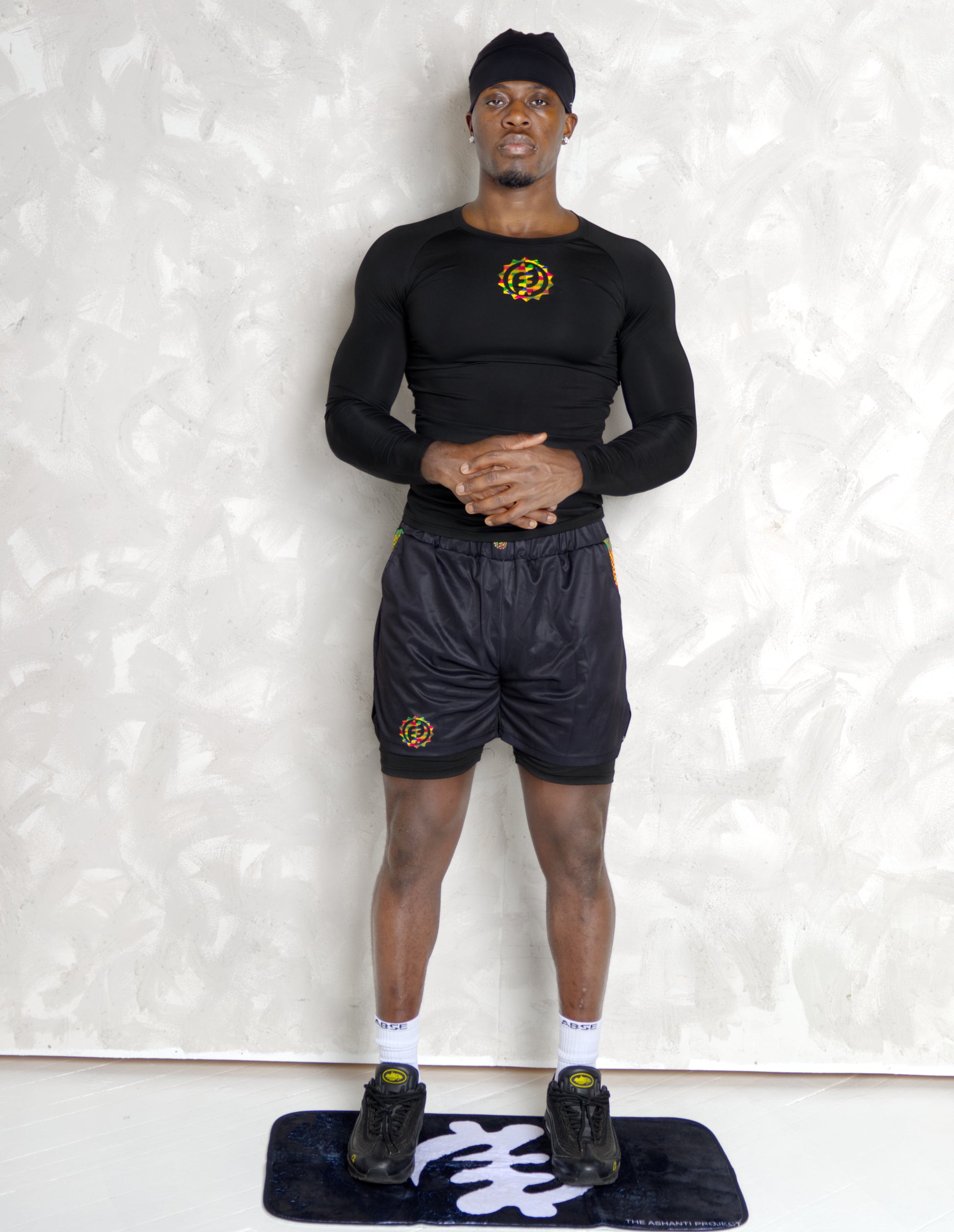 Person wearing a black athletic outfit with kente  logos on a white background. comes with a compression shorts 